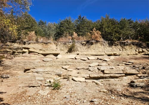 A dry and dusty looking layered rock hill.