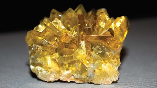 A studio shot of yellow crystals on a black to grey background.