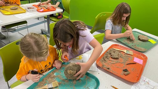Young campers work together to excavate fossil kits. 