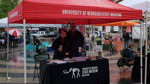 Two friends of the state museum staff a table at an event talking about the museum.