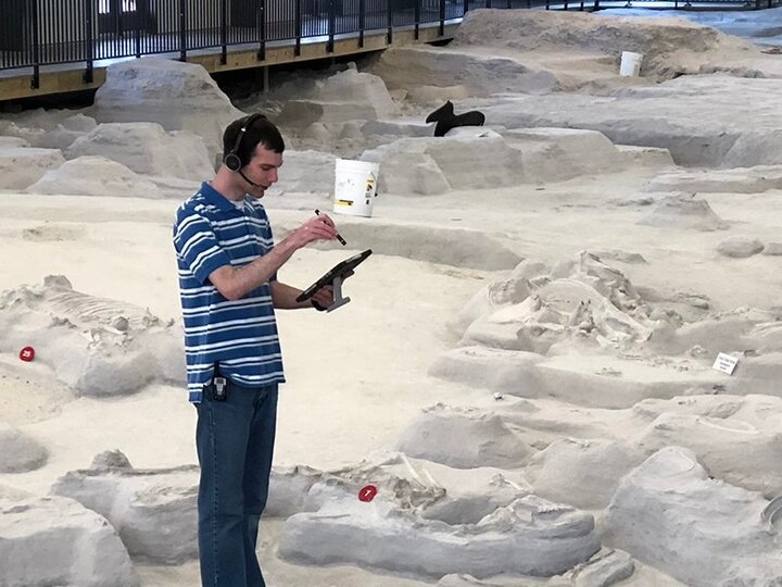 Researcher with headset and mic on digsite with iPad