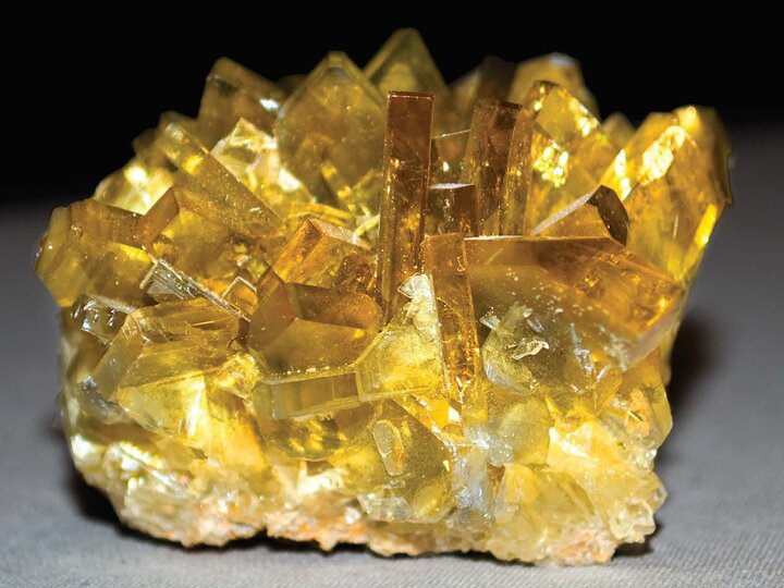 A studio shot of yellow crystals on a black to grey background.