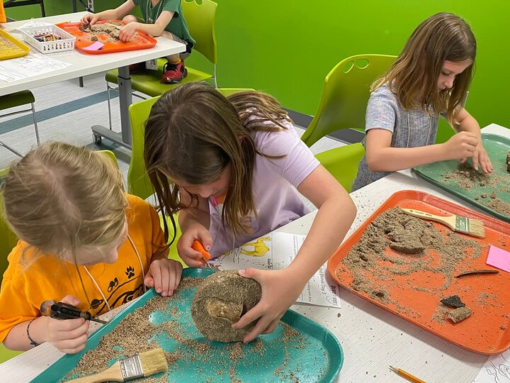 Young campers work together to excavate fossil kits. 