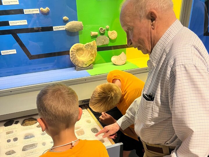 A docent volunteer discusses fossil specimens with two young visitors