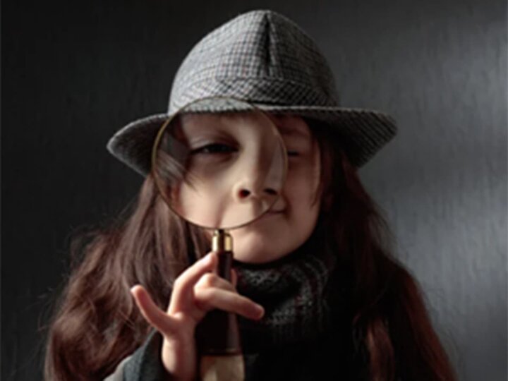 A young child with a Sherlock Holmes style hat and magnifying glass