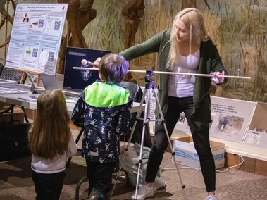 A volunteer demonstrates planetary orbit with a hands-on activity for two young children.