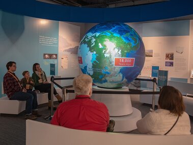 Families watch a video on oceans on the 5-foot globe display, like an inverted planetarium